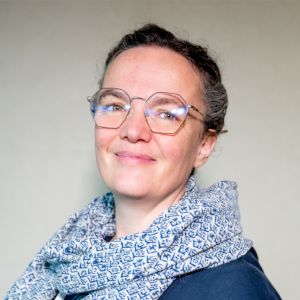 A smiling white woman wearing glasses, a blue scarf and a blue top